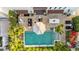 Aerial view of a backyard patio features a fire pit, built-in grill, lounge chairs, and pool surrounded by lush landscaping at 7242 E Joshua Tree Ln, Scottsdale, AZ 85250