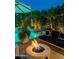 Outdoor living area with a modern fire pit, black outdoor sofa, and a beautiful pool at 7242 E Joshua Tree Ln, Scottsdale, AZ 85250