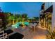A luxury outdoor patio with a dining table, seating area, manicured landscaping, and beautiful pool at 7242 E Joshua Tree Ln, Scottsdale, AZ 85250
