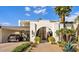 Stunning home exterior with an arched entry, a porte-cochere, beautiful landscaping, and a desert-style garden at 7242 E Joshua Tree Ln, Scottsdale, AZ 85250