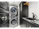 Modern laundry room with stacked washer/dryer, black marble countertop, and sleek cabinetry at 7242 E Joshua Tree Ln, Scottsdale, AZ 85250