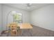 Bright room featuring carpet flooring, a ceiling fan, a wooden desk, and an outdoor view from the window at 7841 N 18Th St, Phoenix, AZ 85020