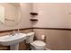 Cozy powder room featuring a pedestal sink, oval mirror, and charming decorative shelves at 100 N 221St Ave, Buckeye, AZ 85326