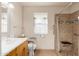 Accessible bathroom featuring a tiled shower with seat and safety bars, along with ample counter space and a window at 10521 W Roundelay Cir, Sun City, AZ 85351
