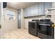 Functional laundry room with modern washer and dryer, ample storage cabinets, and a window for natural light at 10521 W Roundelay Cir, Sun City, AZ 85351