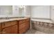 Bright bathroom with granite counters, dual sinks, wood cabinets, a tub, and a large window at 10834 N 45Th St, Phoenix, AZ 85028