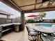 Covered outdoor BBQ island and dining area leading to the pool and desert landscaping at 1203 W Mesquite Tree Ln, San Tan Valley, AZ 85143