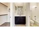 Bathroom featuring a dark vanity, a framed mirror, and access to a walk-in closet and a shower-tub combination at 14561 W Hidden Terrace Loop, Litchfield Park, AZ 85340