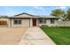 Charming single-story home with a well-manicured lawn, solar panels, and a long concrete driveway at 15031 N 37Th Ave, Phoenix, AZ 85053
