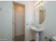 Clean bathroom with a pedestal sink, round mirror with vanity lighting, and a storage closet at 15655 W Bethesda Ct, Surprise, AZ 85374