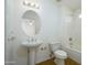 Bright bathroom featuring a pedestal sink, toilet, bathtub with shower, and round mirror with vanity lighting at 15655 W Bethesda Ct, Surprise, AZ 85374