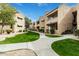 Beautiful condo complex with green lawn, mature trees, and beige colored units under a bright blue sky at 2228 N 52Nd St # 245, Phoenix, AZ 85008