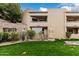 Exterior view of condo showing grassy lawn, stone wall feature, and a balcony with string lights at 2228 N 52Nd St # 245, Phoenix, AZ 85008