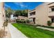 Exterior of condo with landscaped grounds, including a grassy lawn, bushes, and a stone wall feature at 2228 N 52Nd St # 245, Phoenix, AZ 85008