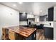 Modern kitchen featuring dark cabinets, stainless steel appliances, and a butcher block island with seating at 2228 N 52Nd St # 245, Phoenix, AZ 85008