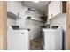 Bright laundry room featuring white washer and dryer, overhead cabinets, and shelving for organized storage at 2228 N 52Nd St # 245, Phoenix, AZ 85008