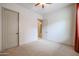 Empty bedroom features neutral carpet, a ceiling fan, and view to an adjacent room at 2320 E Allen St, Phoenix, AZ 85042