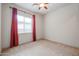 Empty bedroom features neutral carpet, a ceiling fan, and red curtains at 2320 E Allen St, Phoenix, AZ 85042