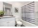 Bright bathroom with a granite countertop vanity, framed mirror, white toilet, and a stylish gray striped shower curtain at 24531 W Cocopah St, Buckeye, AZ 85326