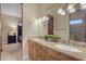 This bathroom offers dual sinks, wooden cabinetry, granite counters, and shower with stone tiling at 2998 E Waterman Way, Gilbert, AZ 85297