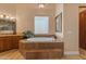 Bright bathroom featuring a soaking tub with tile surround, a window, and vanity with light fixture at 2998 E Waterman Way, Gilbert, AZ 85297
