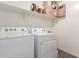 Well-equipped laundry room with washer, dryer, and storage shelf at 37295 W Cannataro Ln, Maricopa, AZ 85138