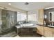 Well-lit bathroom showcasing a bathtub, glass shower, black countertop and light wood cabinets at 4147 W Victoria Ln, Chandler, AZ 85226