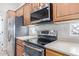 Close-up of kitchen featuring stainless steel appliances, wood cabinets and a quartz countertop at 42019 N Golf Crest Rd, Anthem, AZ 85086