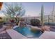 Inviting pool with rock waterfall feature set amongst lush desert landscaping at dusk at 42019 N Golf Crest Rd, Anthem, AZ 85086