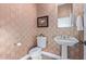 Elegant powder room featuring an ornate pedestal sink, decorative walls and a toilet at 42019 N Golf Crest Rd, Anthem, AZ 85086