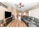 Spacious living room featuring modern flooring, a ceiling fan and a large leather couch at 5002 W Wikieup Ln, Glendale, AZ 85308