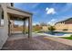Inviting backyard featuring a covered patio, brick pavers, lush artificial turf, and a sparkling pool with a waterfall feature at 504 E Quentin Ln, San Tan Valley, AZ 85140