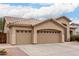 Three-car garage home featuring desert landscaping, a driveway, and a tile roof at 5670 W Irma Ln, Glendale, AZ 85308