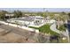 Stunning aerial view of a white modern home with well-manicured lawn, palm trees, and mountain backdrop at 6500 E Cactus Wren Rd, Paradise Valley, AZ 85253