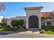 Home exterior featuring an arched gate, white brick, mature landscaping, and a tile roof at 7121 E Mcdonald Dr, Paradise Valley, AZ 85253