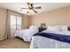Well-lit bedroom with two beds, a ceiling fan, and neutral-toned walls at 714 W Desert Hills Dr, San Tan Valley, AZ 85143
