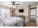 Main bedroom with a ceiling fan, gray bedding, mounted TV, and en-suite access at 714 W Desert Hills Dr, San Tan Valley, AZ 85143