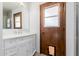 Bathroom vanity with white cabinets, marble countertop, and a wood door with a window at 8476 E Wethersfield Rd, Scottsdale, AZ 85260