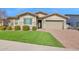 Charming home featuring a well-manicured lawn, brick driveway, and a two-car garage on a sunny day at 13734 W Harvest Ave, Litchfield Park, AZ 85340