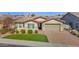 Inviting single-story home with a well-manicured lawn, a brick driveway, and an attached two-car garage at 13734 W Harvest Ave, Litchfield Park, AZ 85340