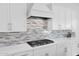 A modern kitchen with white cabinets, quartz countertops, and a stylish backsplash at 13734 W Harvest Ave, Litchfield Park, AZ 85340