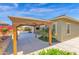 A backyard pergola offers a shaded retreat next to the home's exterior, surrounded by desert landscaping at 13734 W Harvest Ave, Litchfield Park, AZ 85340