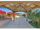A backyard pergola offers shade, situated amidst lush landscaping and hardscape elements at 13734 W Harvest Ave, Litchfield Park, AZ 85340