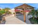 A wooden pergola shades an outdoor space, complemented by vibrant bougainvillea and desert landscaping at 13734 W Harvest Ave, Litchfield Park, AZ 85340