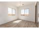 Bright, sun-filled living room with wood-look tile floors, modern light fixture, and multiple windows at 21960 E Saddle Ct, Queen Creek, AZ 85142