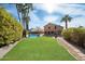Expansive backyard featuring a sparkling pool, lush green lawn, mature landscaping, and charming patio area for outdoor enjoyment at 23225 N 23Rd Pl, Phoenix, AZ 85024