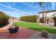 A lush backyard with a cozy fire pit, manicured lawn, mature trees, and a desert landscape at 23225 N 23Rd Pl, Phoenix, AZ 85024