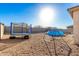 Spacious backyard with gravel and block wall, featuring a trampoline and inflatable pool for outdoor fun at 25913 W Cat Balue Dr, Buckeye, AZ 85396