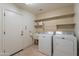 Functional laundry room with washer, dryer, utility sink, shelving, and exterior access at 26711 N 21St Dr, Phoenix, AZ 85085