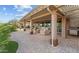Covered back patio with pavers, comfortable seating, and a built-in grill for outdoor dining at 27248 W Mohawk Ln, Buckeye, AZ 85396